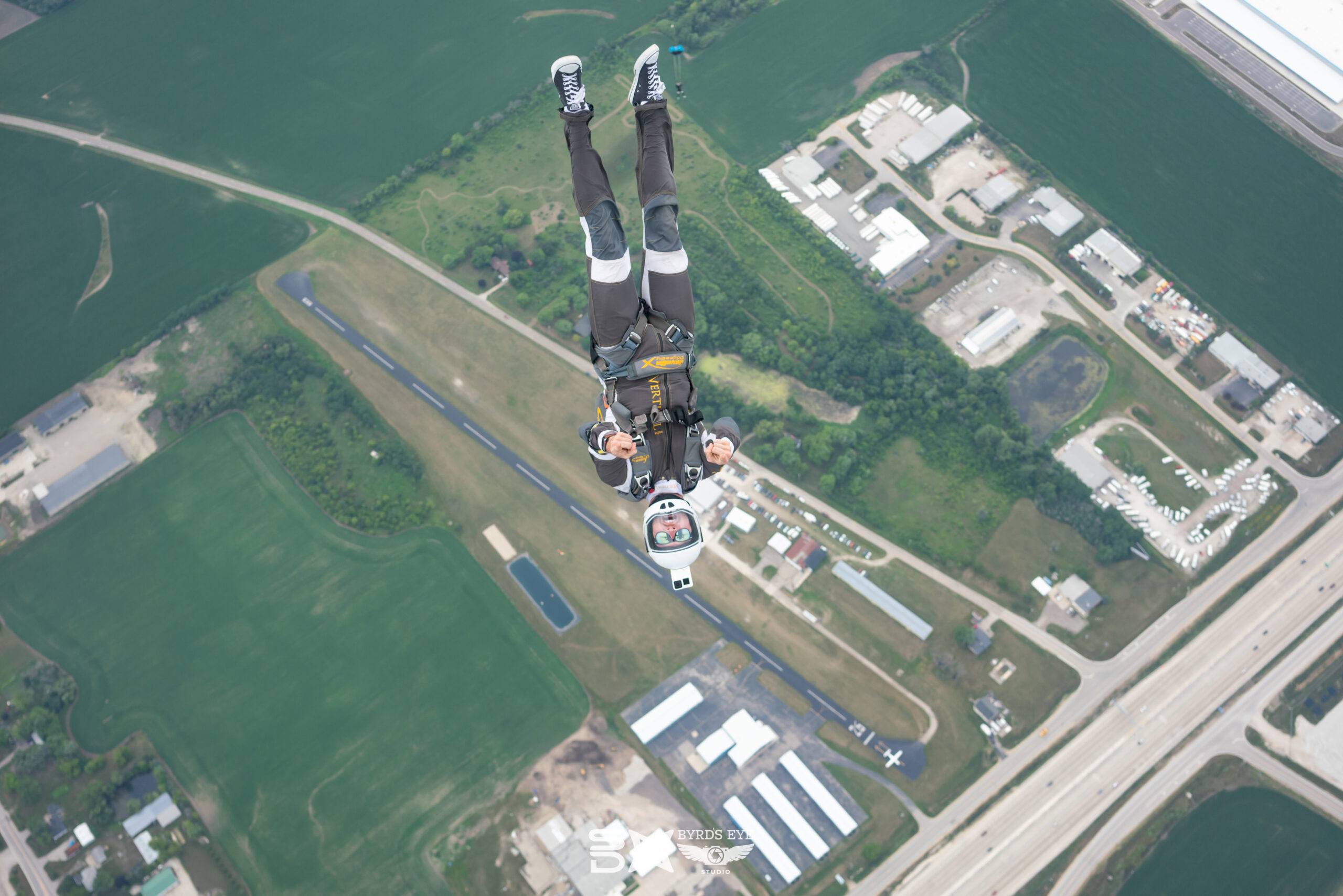 skydiver points to the camera after jumping from a plane.