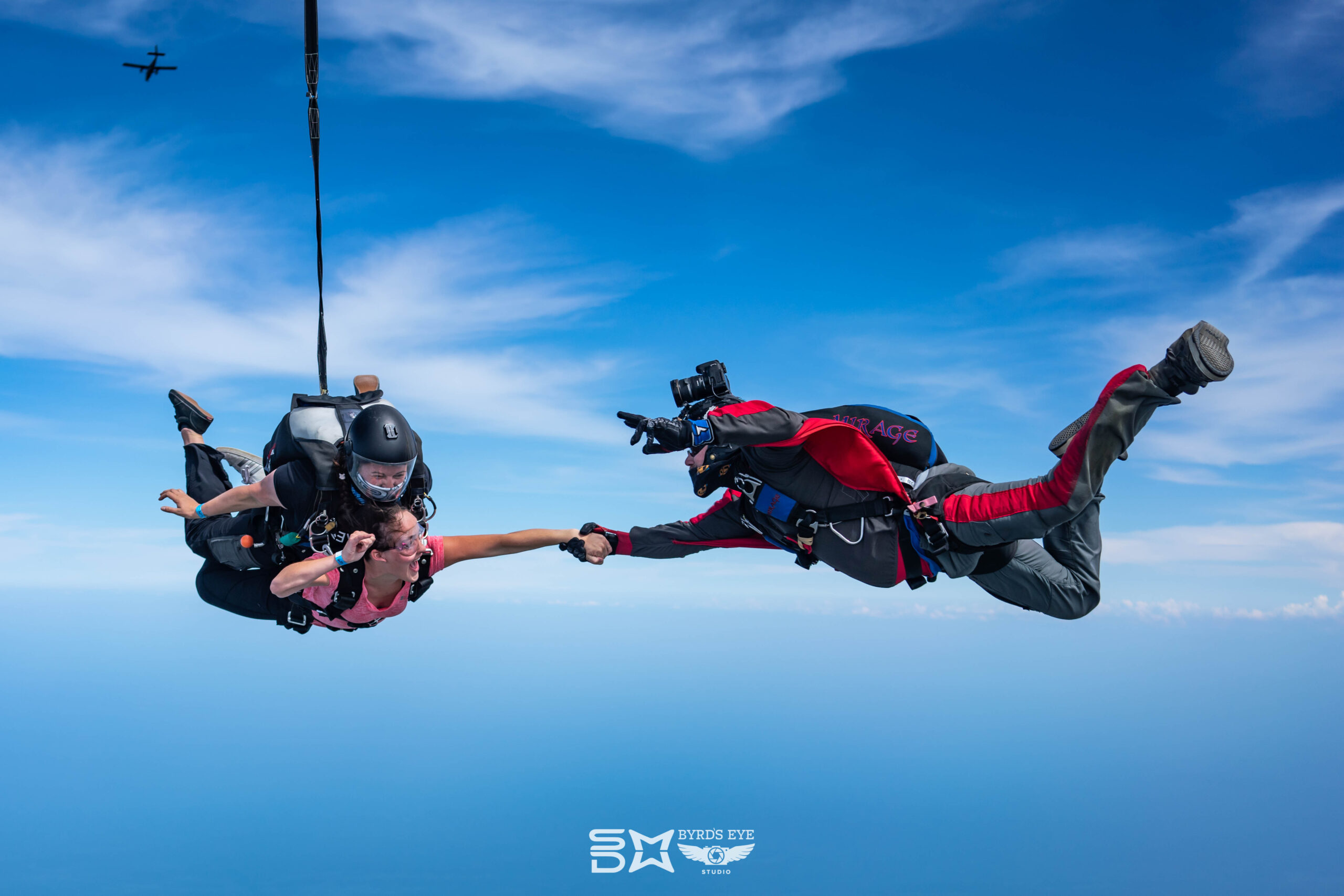 Tandem Skydive with outside videographer holding hands with tandem student.